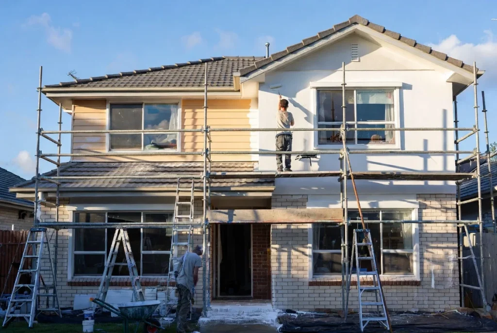 Professional team painting a home exterior, showcasing factors that influence how much does it cost to paint a house.
